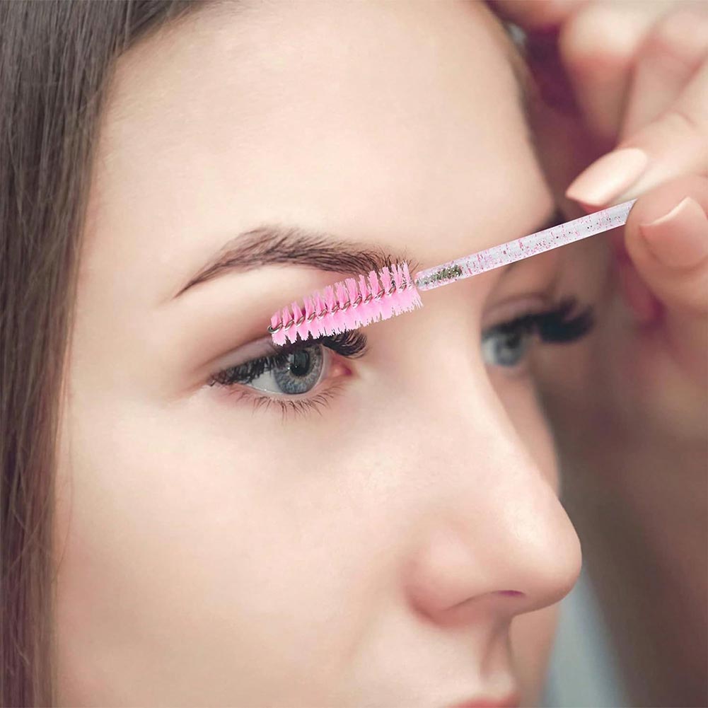 A woman is brushing her eyelashes with an eyelash brush