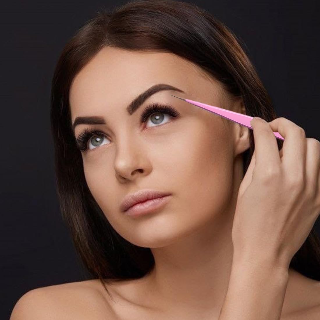 A woman is using straight eyelash tweezers to do eyelash extensions