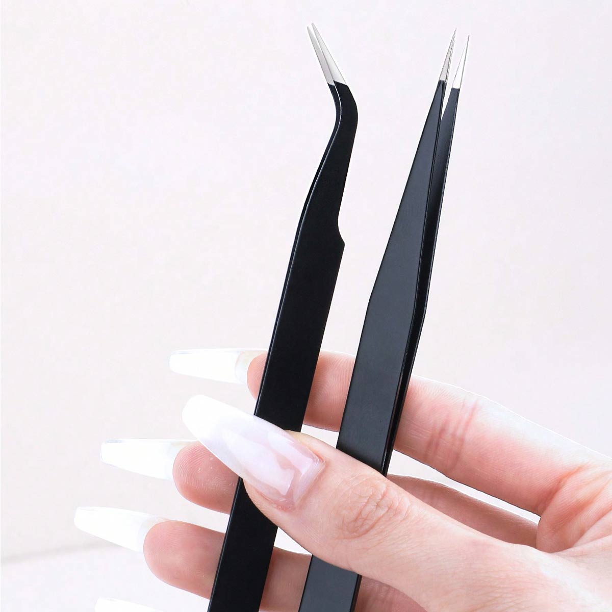 Hands holding straight eyelash tweezers and curved eyelash tweezers